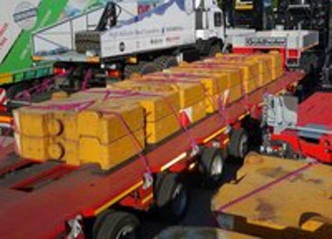 Schwerlasttransport mit gelben Gewichten, gesichert durch RUD-Zurrketten auf Tieflader.