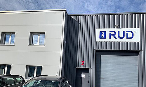 Außenansicht des Gebäudes von RUD Lifting France mit Firmenlogo und geparkten Autos.