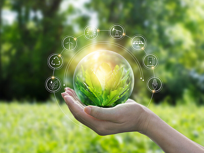 Hand hält gläserne Kugel mit grünen Blättern, umgeben von Symbolen für Nachhaltigkeit und Umwelt.