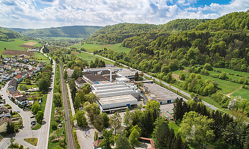 Luftaufnahme des RUD Firmengebäudes inmitten grüner Landschaft mit umliegenden Wohngebieten.