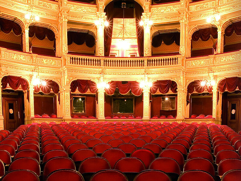 Prunkvoller Theatersaal mit roten Samtsitzen und goldverzierten Logen.