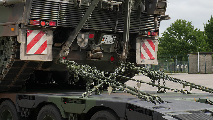 Ketten und Spannsysteme sichern einen Militärpanzer auf einem Tieflader für den Transport.