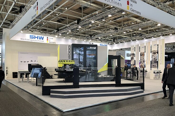 SHW-Messestand auf einer Industriemesse mit Maschinenpräsentation und Besucherbereich.
