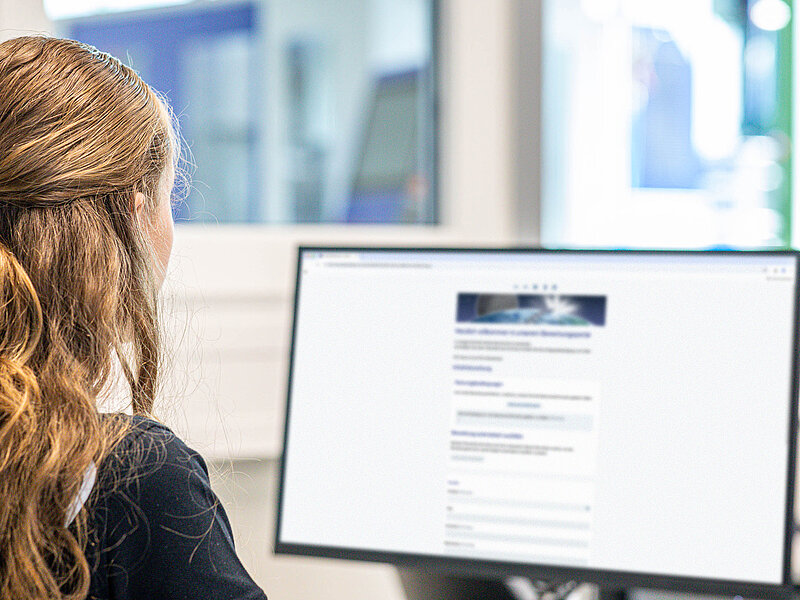 Eine junge Frau sitzt vor einem Computer und füllt ein Online-Bewerbungsformular von RUD aus.