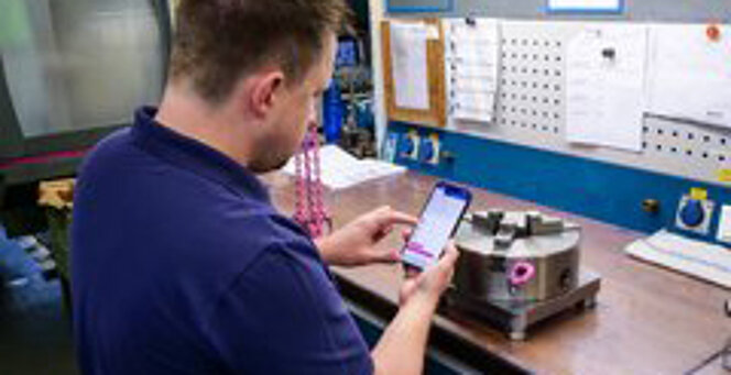 Mitarbeiter verwendet den RUD Anschlagmittel-Konfigurator am Smartphone.