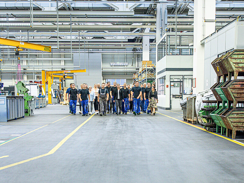 Gruppe von RUD-Mitarbeitenden läuft gemeinsam durch eine moderne Produktionshalle.