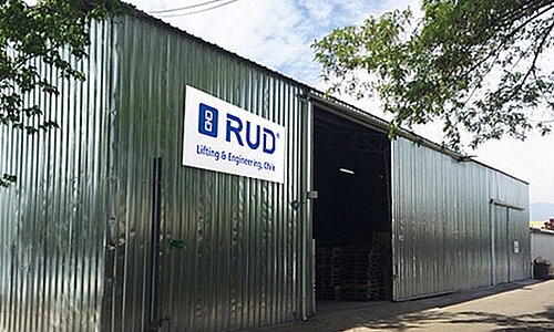 RUD SpanSet Chile Standort mit silberner Wellblechhalle, großem RUD Logo an der Fassade und geöffneter Eingangshalle.
