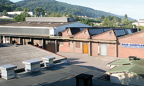 Außenansicht des RUD Schöttler Werksgebäudes mit Backsteinfassade und Firmenlogo.