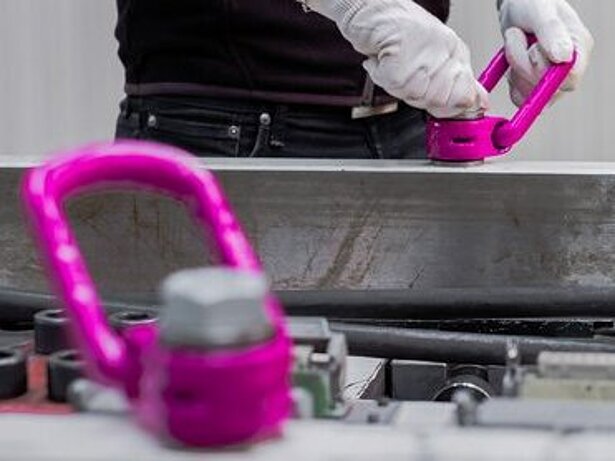Ein Arbeiter befestigt einen RUD Anschlagpunkt VLBG-PLUS an einem schweren Metallbauteil für den sicheren Lastentransport.