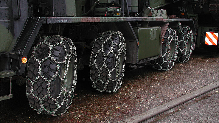 Nahaufnahme der Räder eines Militärfahrzeugs mit montierten RUD Gleitschutzketten für optimale Traktion.