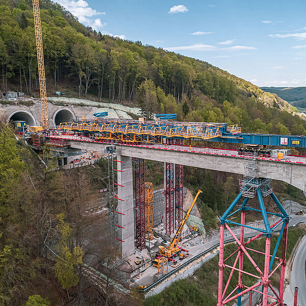 Brückenbauarbeiten an der Filstalbrücke mit großem Montagegerüst, Kränen und Tunnelportalen im Hintergrund.