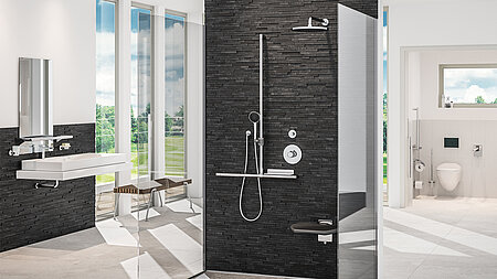 Modernes, barrierefreies Badezimmer mit schwarzer Natursteinwand in der Dusche, höhenverstellbarem Waschbecken, Duschsitz, Haltegriffen und angrenzendem, rollstuhlgerechtem WC-Bereich.