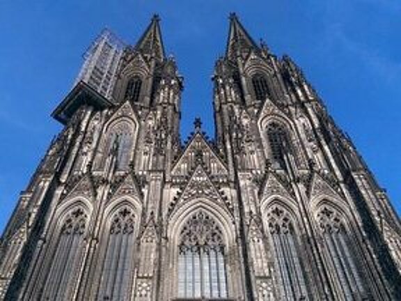 Der Kölner Dom mit seinen beiden Türmen, einer davon mit einem montierten Hängegerüst für Restaurierungsarbeiten.