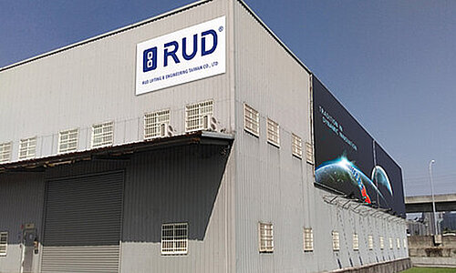 RUD Lifting & Engineering Taiwan Co., Ltd., graues Industriegebäude mit großem RUD Logo und seitlichem Wandbanner mit Globus-Motiv.