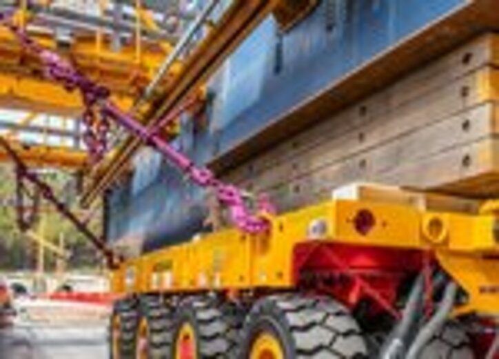 Ein Schwerlast-Transportfahrzeug sichert einen Brückenträger mit RUD ICE-Zurrketten und Holzunterlagen für den sicheren Halt.