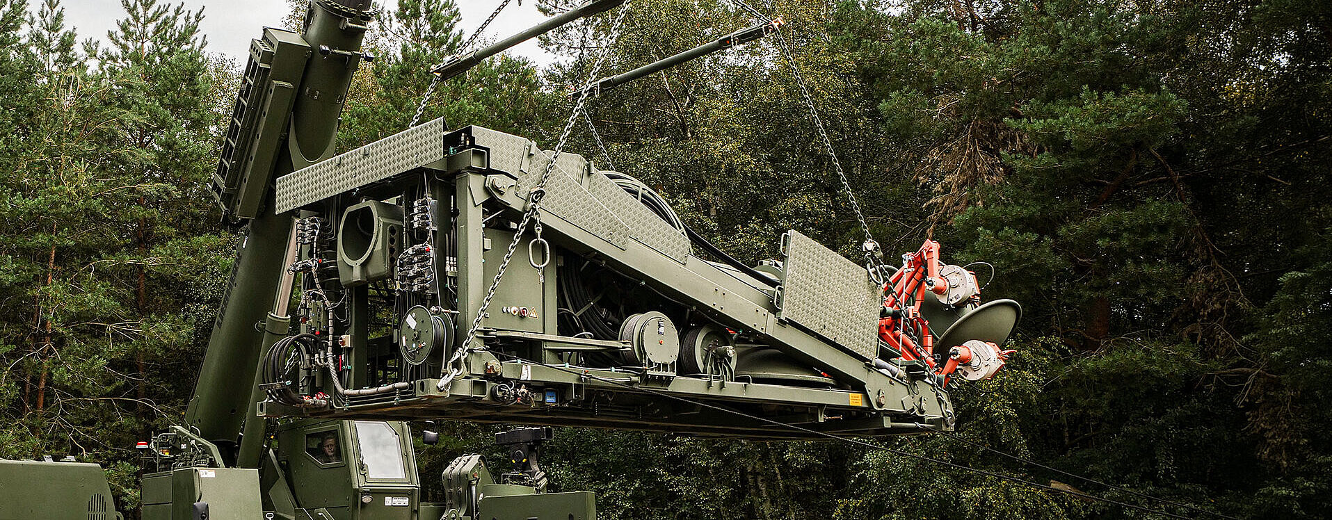 Militärischer Kran hebt technische Ausrüstung mit RUD Anschlagsystemen im Gelände an