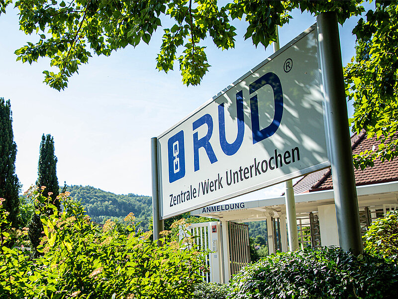 Eingangsschild der RUD-Zentrale im Werk Unterkochen mit Blick auf Natur und Grünanlagen.