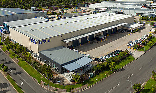 RUD Chains Pty Ltd Standort in Australien, modernes Industriegebäude mit großem RUD Logo, mehreren Ladebuchten und angrenzendem Parkplatz.