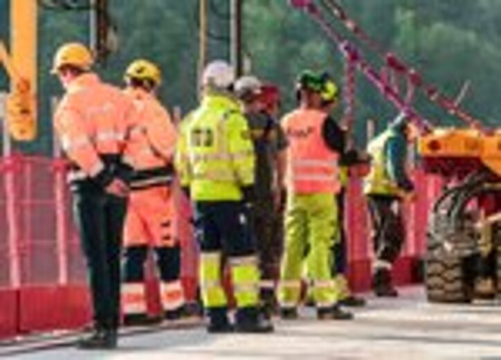 Mehrere Bauarbeiter in Schutzkleidung stehen auf der Baustelle und überwachen die Sicherung mit RUD ICE-Zurrketten.