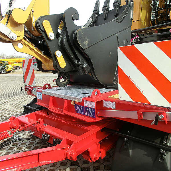 Sicherer Transport eines Baggerarms auf einem roten Tieflader mit RUD-Anschlagpunkten.