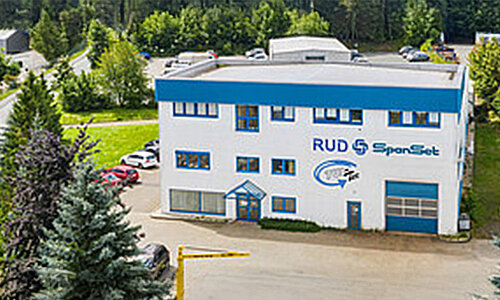 Gebäude der RUD SpanSet GmbH in Plauen mit Firmenlogo an der Fassade, umgeben von Bäumen und Parkplätzen.