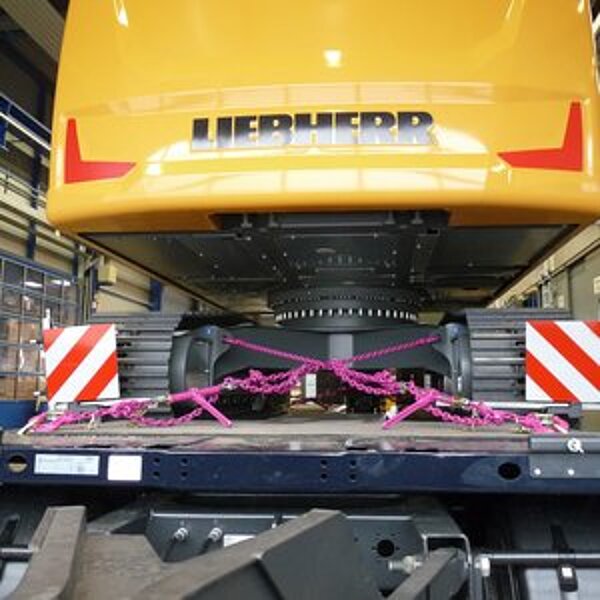 Baumaschine mit RUD Optilash Click System zur Ladungssicherung auf einem Tieflader befestigt.