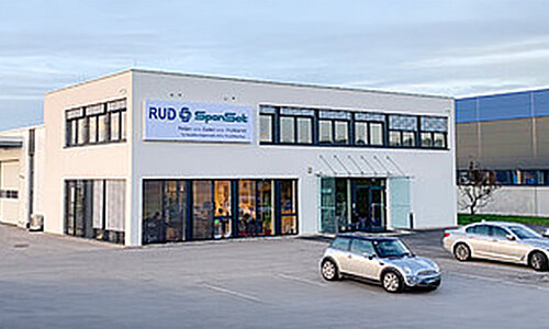 Gebäude der RUD SpanSet GmbH Niederlassung Friedburg mit Logo an der Fassade und geparkten Autos.