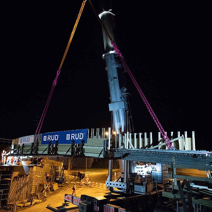 RUD-Hebeketten im nächtlichen Einsatz beim Brückenbau mit großem Kran.