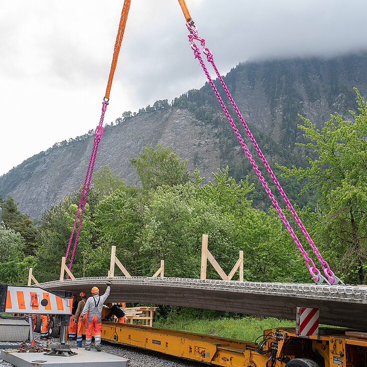 Montage einer Brücke mit RUD-Hebeketten vor einer malerischen Bergkulisse.