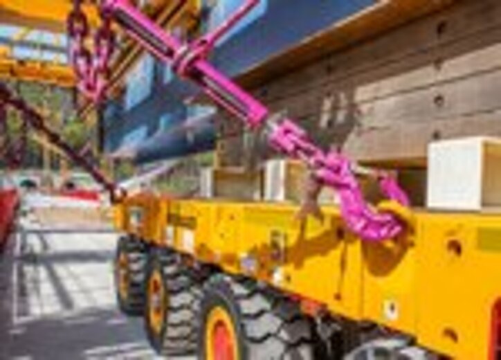 Ein schwerer Brückenträger wird mit RUD ICE-Zurrketten auf einem gelben Schwerlast-Transportfahrzeug gesichert.