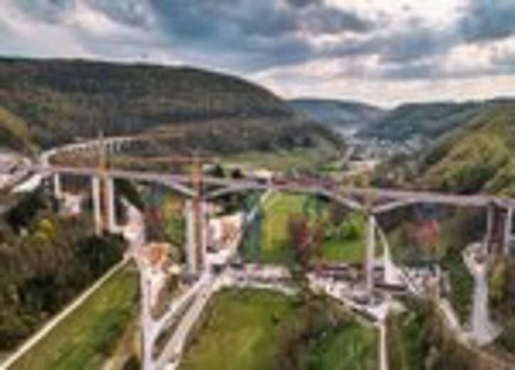 Großbaustelle der Filstalbrücke mit mehreren Pfeilern und Baukränen inmitten einer hügeligen Landschaft.