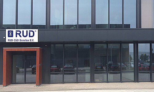 Eingangsbereich des Gebäudes von RUD C&D Benelux B.V. mit großem Glasfassaden-Design und Firmenlogo.