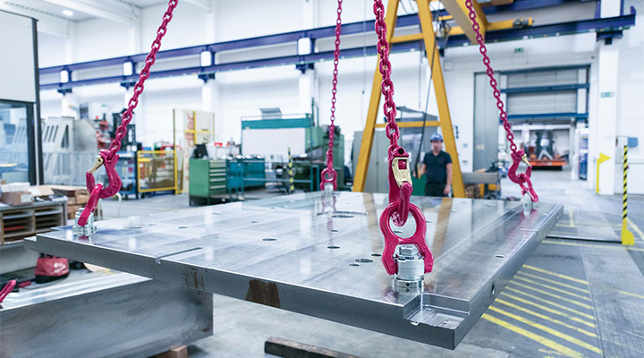 Schwerlastplatte wird in moderner Industriehalle mit RUD-Anschlagpunkten und Kettengehängen sicher gehoben.