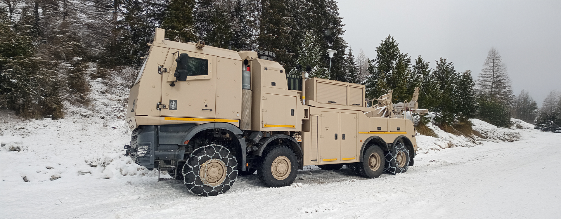 Militärisches Bergefahrzeug im Wintereinsatz mit RUD Gleitschutzketten für sicheren Halt auf Schnee.