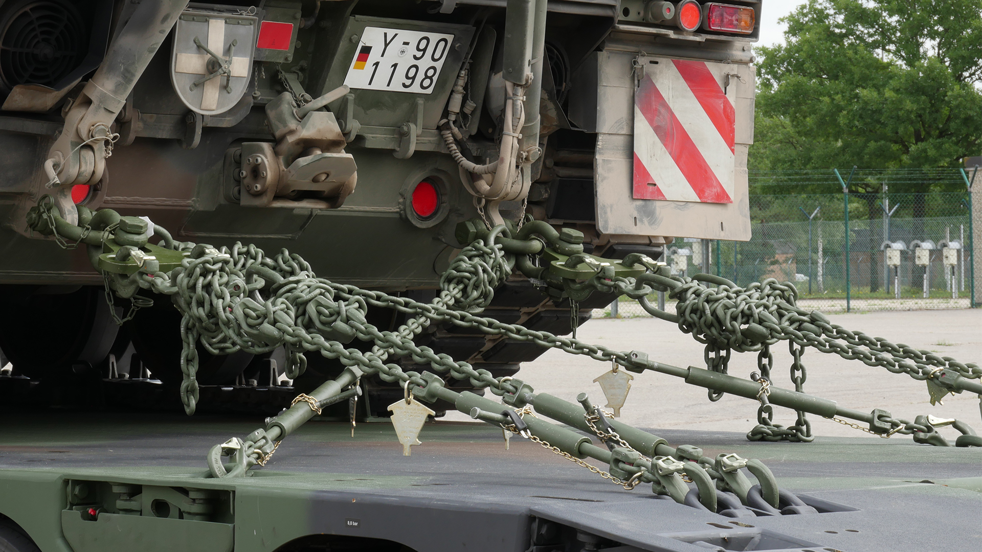 Militärfahrzeug wird mit robusten Ketten und Spannsystemen auf einem Tieflader gesichert.
