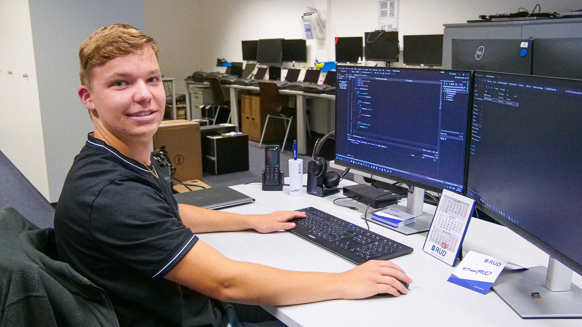 Auszubildender Fachinformatiker bei RUD programmiert an zwei Monitoren im Büro.
